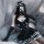 A person wearing a black lolita maid costume sleepwear set, featuring lace trimmings, a bow headband, gloves, and stockings, ...