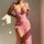 A woman poses in a sheer pink dress adorned with rose patterns, featuring lace trim, an underwire bra, and a high slit, perfe...