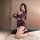 Woman in feiniao kuiyue sheer purple lingerie set with long sleeves and bodycon skirt, posing on bed with wine glass.