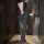 Woman in black backless lace dress holding wine glass, showcasing elegant silhouette and alluring design.