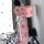 A woman stands by a window wearing a pink floral japanese kimono-style dress with a white ribbon belt, set against a backdrop...