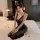A woman sits on a bed wearing a black sheer mesh nightgown with deep v-neck and sleeveless design, adorned with lace details ...