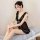A woman sits elegantly on a bed wearing a sheer black lace sleepwear set, featuring delicate ruffles and a soft tulle skirt, ...