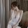 A woman models a white lace sleepwear set, featuring delicate floral patterns and thin straps, perfect for intimate wear with...