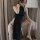 A woman poses elegantly in a black sheer lace sleep dress, featuring a high neck and side slit, perfect for a sexy yet sophis...