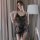 A woman poses elegantly in a sheer black long night seductive lingerie set, featuring delicate lace and a flowing design, per...
