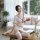 A woman poses elegantly on a table wearing a sheer white long night set with black trim, featuring a stylish design perfect f...