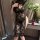 A woman poses in a black lace dress with a high slit, revealing a red rose nearby. the elegant design features intricate flor...