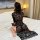 A woman sits on a bed wearing a black lace dress, featuring sheer mesh and long sleeves, highlighting a seductive design perf...