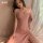 A woman wearing a soft pink sleep dress by jun mu fei, featuring spaghetti straps, a side slit, and sheer fabric design.