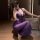 Woman wearing purple lace deep v sheer mesh sleep dress with bow-tie straps, posing in a modern room.