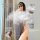 A woman poses with steam, showcasing a backless dress highlighting her bust and thighs. the design features high slits and se...