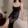 Woman wearing a black sheer mesh slip dress with a high split, styled as sexy lingerie and sleepwear on a bed.