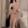 Woman in pink mesh slip dress with high split, holding a rose beside bed — sheer temptation lingerie nightgown set.