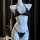 Black sheer lingerie-style bikini set on mannequin, featuring triangle top with ties and matching thong bottom, displayed aga...