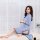 Woman wearing blue sheer mesh qipao nightgown with black trim, sitting on bed in soft light.
