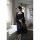 A woman stands by a window wearing a black lace sleep set, featuring a sheer nightgown and matching bralette, perfect for sed...