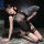 A woman poses elegantly in a sheer black cheongsam with lace detailing, high-slit design, and fishnet stockings, holding a de...