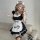 A woman wearing a black and white maid costume cosplay dress, featuring a ruffled apron with paw prints, holding a teddy bear...