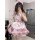 A woman wearing a cute maid costume cosplay outfit, featuring a pink lolita dress with ruffles, bows, and a cat paw design, p...