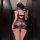 Woman wearing black manny night elegant lace halter bodysuit with sheer mesh and cutout back, posing in a hallway.