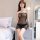 Woman wearing manny night sheer mesh bodysuit set with see-through lace thong and skirt, posing seductively in bedroom.