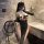 Woman in mannyan dark nun cosplay bodysuit with black and white design, holding a whip in a marble bathroom.
