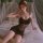 Woman in mannyan french-style lace chemise, sheer sexy sleep dress, lightweight bodycon nightgown on bed with soft lighting.