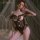 Woman wearing mannyan sheer lace bodysuit with open-crotch design, underwire push-up, and bow details on bed.
