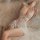 Woman wearing white mannyan lace bodysuit sleep dress, backless halter design, lying on sheer fabric bedding.