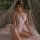 Woman wearing mannyan sensual lace bodysuit, sheer hook-neck open-crotch sleepwear, posing on bed with romantic lighting.