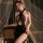 Woman wearing mannyan sexy lace bodysuit dress - sheer mesh cut-out halter bodycon nightwear, posing elegantly by vintage cha...