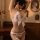 Woman wearing mannye qing white feathered backless thong bodysuit with bow detail, seductive wife style lingerie set.