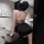 A woman poses in a stylish room, wearing a sheer purple dress with a floral pattern and black stockings. the outfit features ...