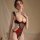 Woman modeling mannye qing red and black lace bodysuit with underwire, open-crotch design, and ruffled straps.