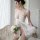 A woman poses elegantly in a white lace chemise with a sexy cut-out design, holding white flowers. the sheer fabric adds a to...