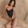 Woman modeling black mannye qing sensual bodysuit with open-crotch design, posing on bed for intimate moments.