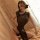 Woman wearing black sheer cheongsam lingerie with high slit, posing seductively on bed — mannye qing sensual role play dress.
