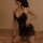 Woman wearing black lace bodysuit with halter neck and open back, featuring sheer panels and side ties for shaping.