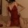 Woman wearing red lace bodysuit with halter neck and shaping design, posing on bed. mannye qing back plus size lingerie set.