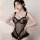 Woman modeling black sheer polka dot bodysuit with lace trim and pearl chain detail at hem.