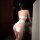 A woman stands facing away from the camera, wearing a white mannyqing bodysuit with a deep v-neckline and open-crotch design....