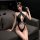 A woman poses on a couch wearing a black mannyqing bodysuit featuring a deep v-neckline, sheer design, and open-crotch style,...