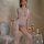 Woman modeling mannyqing sheer lace bodysuit with spiderweb cutouts and open-crotch design in elegant bedroom setting.