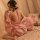A woman sits gracefully on a bed wearing a pink mannyqing japanese kimono sleepwear robe adorned with cherry blossom prints. ...