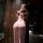 A woman stands facing away from the camera, wearing a sheer pink mannyqing lingerie dress. the dress features a high slit and...