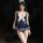 A stylish navy blue jumpsuit featuring a sailor design with white accents, a bow tie, lace-up details, and cutouts for a femi...