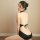 A woman poses in a black lace-back swimsuit with a deep cutout design, showcasing elegant vintage style.