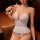 Woman wearing white open-crotch bodysuit with ruffled hem and halter neck, seated in dimly lit room.