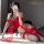 A woman poses in a red manyan halter bodice set with floral embroidery, paired with sheer stockings and matching thigh-high s...